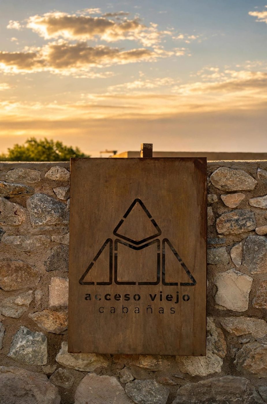 El cartel de Acceso Viejo en el muro de piedra, al atardecer